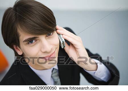 Young man in suit using cell phone, smiling at camera, high angle view View Large Photo Image Stock Image - Young man in suit using cell phone, smiling at camera, high angle view. Fotosearch