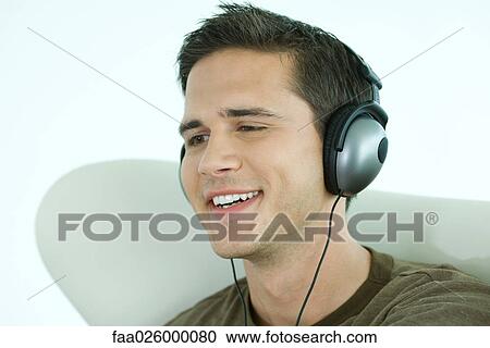 Young man listening to headphones, smiling, close-up View Large Photo Image Stock Image - Young man listening to headphones, smiling, close-up. Fotosearch