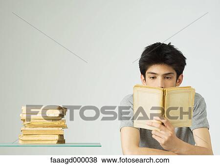 Stock Photo - Young man reading books. Fotosearch