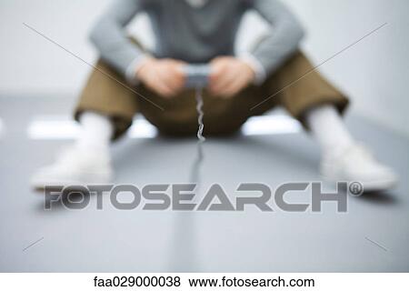 Young man sitting on the ground, holding video game controller, cropped view, defocused View Large Photo Image Stock Photo - Young man sitting on the ground, holding video game controller, cropped view, defocused. Fotosearch