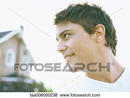 Young man smiling, house in background View Large Photo Image Stock Photo - Young man smiling, house in background. Fotosearch