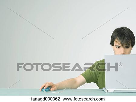 Stock Image - Young man using laptop computer. Fotosearch