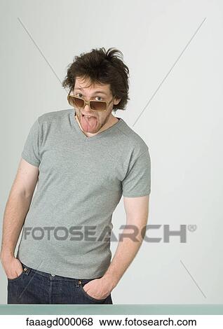 Young man wearing sunglasses, sticking out tongue View Large Photo Image Stock Photo - Young man wearing sunglasses, sticking out tongue. Fotosearch