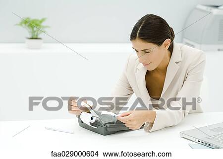 Young professional using adding machine, holding receipt View Large Photo Image Picture - Young professional using adding machine, holding receipt. Fotosearch