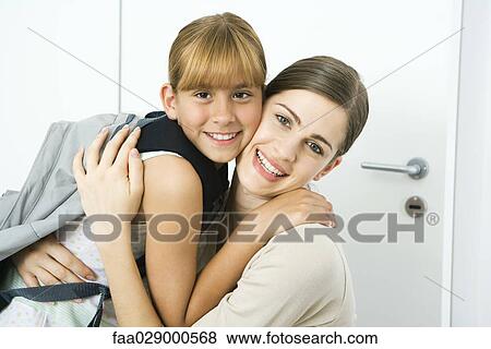 Stock Photo - Young woman and preteen girl embracing, smiling at camera. Fotosearch