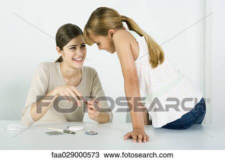 Young woman and preteen sister looking at cosmetics together, smiling View Large Photo Image Stock Image - Young woman and preteen sister looking at cosmetics together, smiling. Fotosearch