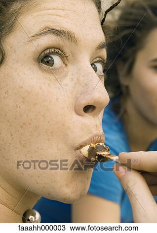 Stock Image - Young woman eating ice cream. Fotosearch