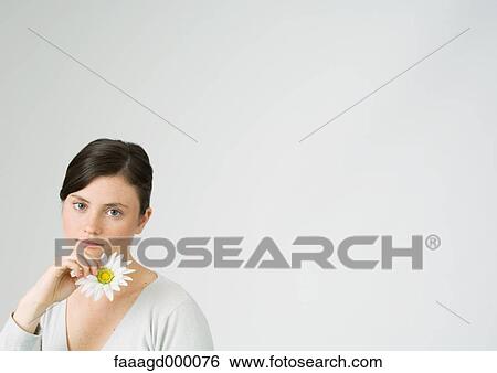 Stock Photograph - Young woman holding daisy. Fotosearch