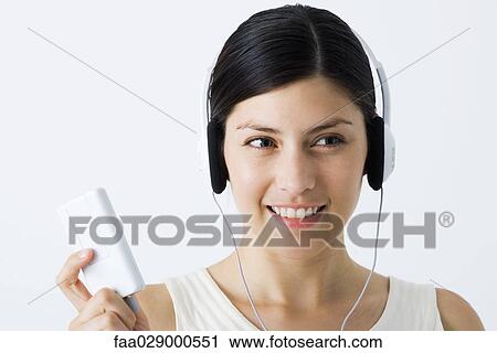 Young woman listening to MP3 player, smiling View Large Photo Image Stock Image - Young woman listening to MP3 player, smiling. Fotosearch