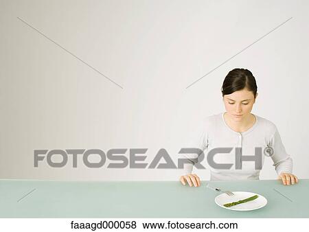 Young woman looking down at single asparagus on plate View Large Photo Image Stock Photo - Young woman looking down at single asparagus on plate. Fotosearch