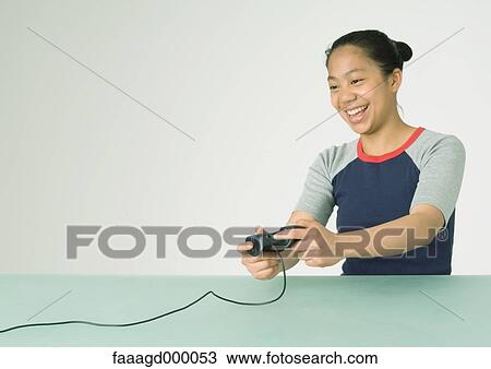 Stock Image - Young woman playing video game. Fotosearch