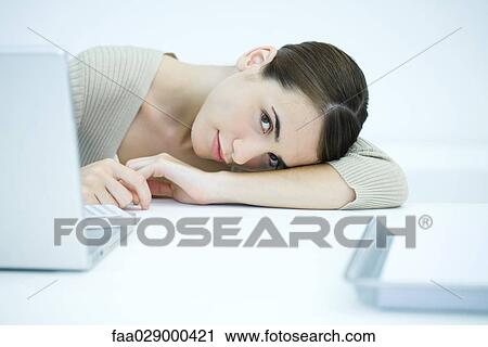 Young woman sitting at desk with head down on arm View Large Photo Image Stock Image - Young woman sitting at desk with head down on arm. Fotosearch
