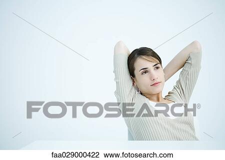 Young woman sitting with hands behind head View Large Photo Image Stock Image - Young woman sitting with hands behind head. Fotosearch