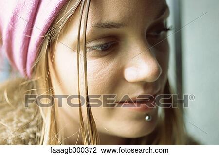 Stock Image - Young woman with facial piercing, close-up. Fotosearch