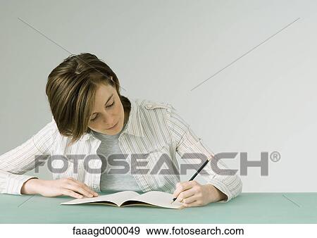 Stock Photo - Young woman writing in notebook. Fotosearch