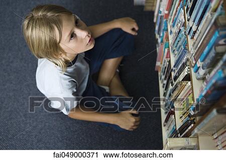 Boy sitting on floor looking up at shelves full of books View Large Photo Image Stock Image - Boy sitting on floor looking up at shelves full of books. Fotosearch