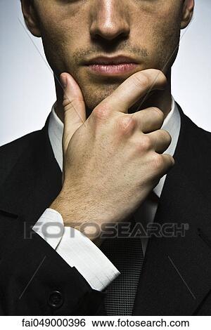 Businessman with hand under chin, portrait View Large Photo Image Stock Photograph - Businessman with hand under chin, portrait. Fotosearch