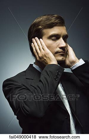 Stock Photo - Businessman with hands covering ears and eyes closed. Fotosearch