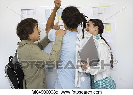 College student looking at results posted on bulletin board raising fist, classmates congratulating, rear view View Large Photo Image Stock Photography - College student looking at results posted on bulletin board raising fist, classmates congratulating, rear view. Fotosearch
