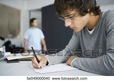 College student writing at desk in classroom View Large Photo Image Stock Image - College student writing at desk in classroom. Fotosearch