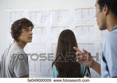 College students chatting, female student checking bulletin board in background View Large Photo Image Stock Photo - College students chatting, female student checking bulletin board in background. Fotosearch