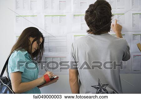 College students checking bulletin board, woman writing in agenda View Large Photo Image Stock Image - College students checking bulletin board, woman writing in agenda. Fotosearch