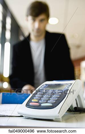 Credit card reader on checkout counter, customer in background View Large Photo Image Stock Photograph - Credit card reader on checkout counter, customer in background. Fotosearch