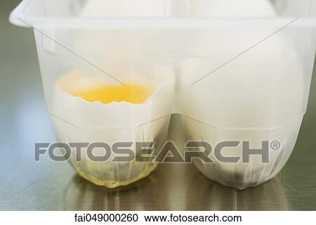 Eggs in carton, one cracked open View Large Photo Image Stock Image - Eggs in carton, one cracked open. Fotosearch