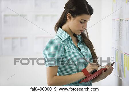 Female college student at bulletin board writing in agenda View Large Photo Image Stock Photo - Female college student at bulletin board writing in agenda. Fotosearch