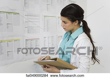 Female college student looking at information posted on bulletin board View Large Photo Image Picture - Female college student looking at information posted on bulletin board. Fotosearch