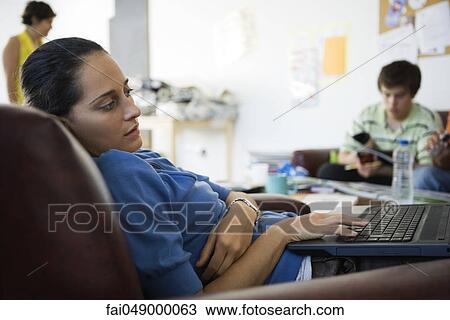 Female college student lounging in armchair using laptop computer View Large Photo Image Stock Image - Female college student lounging in armchair using laptop computer. Fotosearch
