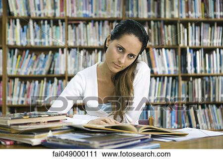 Female college student reading book at table in library, looking at camera View Large Photo Image Stock Image - Female college student reading book at table in library, looking at camera. Fotosearch