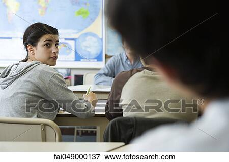 Female high school student looking over shoulder at classmate View Large Photo Image Stock Photo - Female high school student looking over shoulder at classmate. Fotosearch