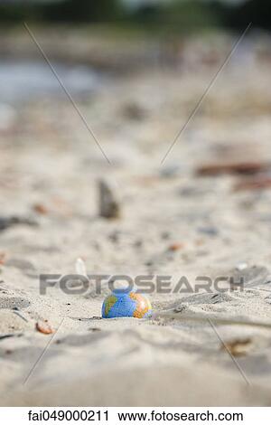 Stock Image - Globe partially buried in sand. Fotosearch