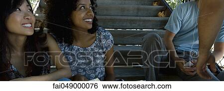 Group of young adult friends hanging out together outdoors View Large Photo Image Stock Photograph - Group of young adult friends hanging out together outdoors. Fotosearch