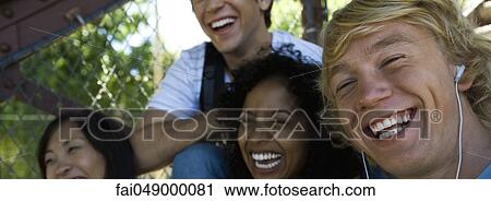 Group of young adult friends laughing together, outdoors, focus on young man in foreground View Large Photo Image Stock Image - Group of young adult friends laughing together, outdoors, focus on young man in foreground. Fotosearch