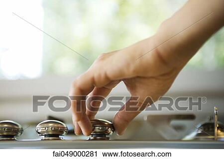 Stock Image - Hand adjusting stove knob. Fotosearch