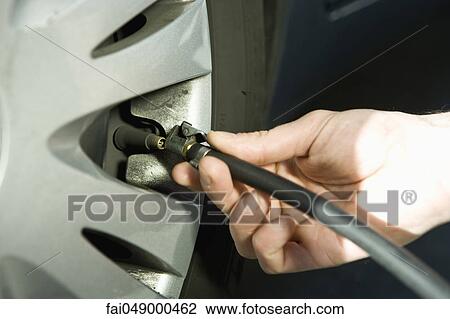 Stock Image - Inflating vehicle tire using air pump hose. Fotosearch