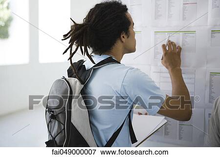 Male college student checking bulletin board View Large Photo Image Stock Photo - Male college student checking bulletin board. Fotosearch