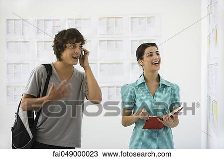 Male college student checking results on bulletin board, talking on cell phone, friend standing nearby View Large Photo Image Stock Image - Male college student checking results on bulletin board, talking on cell phone, friend standing nearby. Fotosearch