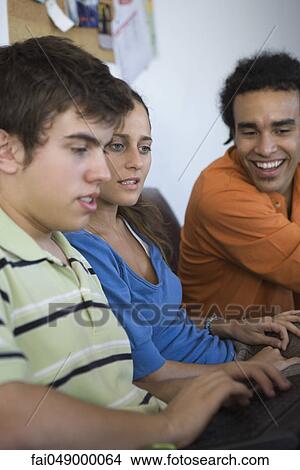 Picture - Male college student using laptop computer, classmates sitting alongside watching. Fotosearch