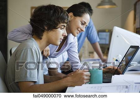Male college student using laptop computer, female classmate looking over shoulder at laptop, smiling View Large Photo Image Stock Image - Male college student using laptop computer, female classmate looking over shoulder at laptop, smiling. Fotosearch