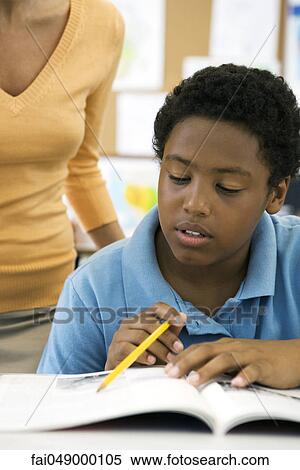 Male elementary school student reading in class while teacher observes View Large Photo Image Stock Photography - Male elementary school student reading in class while teacher observes. Fotosearch