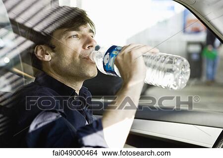 Man drinking bottled water while driving View Large Photo Image Picture - Man drinking bottled water while driving. Fotosearch