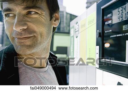 Man finishing at gas pump preparing to leave View Large Photo Image Picture - Man finishing at gas pump preparing to leave. Fotosearch