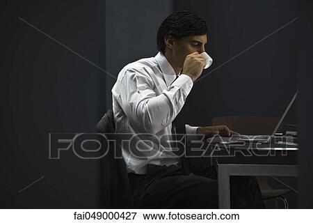 Man in office drinking coffee, working late View Large Photo Image Stock Photo - Man in office drinking coffee, working late. Fotosearch