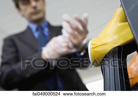 Man putting putting on disposable gloves preparing to refuel vehicle View Large Photo Image Picture - Man putting putting on disposable gloves preparing to refuel vehicle. Fotosearch