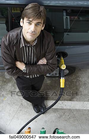 Man standing with arms folded refueling vehicle at gas station View Large Photo Image Stock Photo - Man standing with arms folded refueling vehicle at gas station. Fotosearch