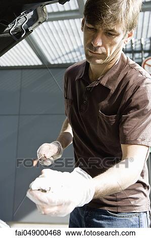 Mechanic checking vehicle motor oil View Large Photo Image Stock Photo - Mechanic checking vehicle motor oil. Fotosearch
