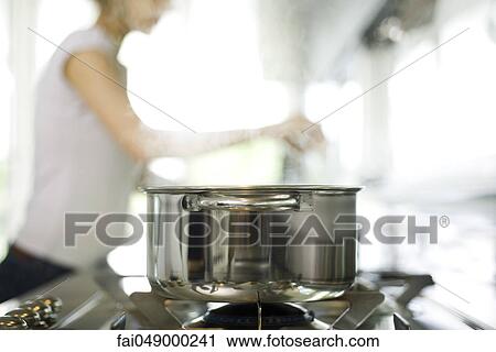 Pot cooking on stove, woman in background View Large Photo Image Stock Image - Pot cooking on stove, woman in background. Fotosearch